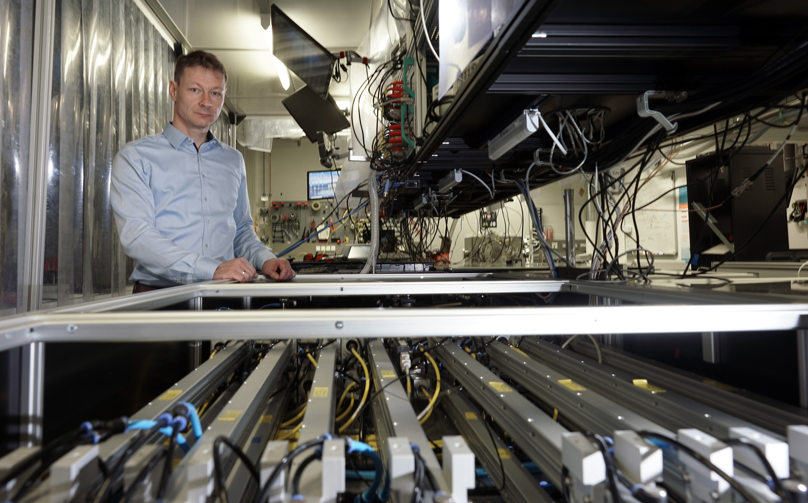 Prof. Dr. Jens Limpert im Labor neben dem technischen Aufbau des Hochleistungsfaserlasersystems zur Erzeugung kohärenter Laserpulse.