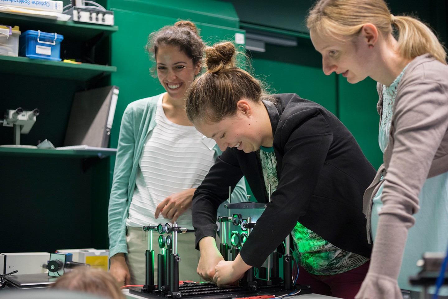 Drei Frauen justieren lächelnd ein Gerät zur adaptiven Optik am Fraunhofer IOF am Wissenschaftscampus 2016.