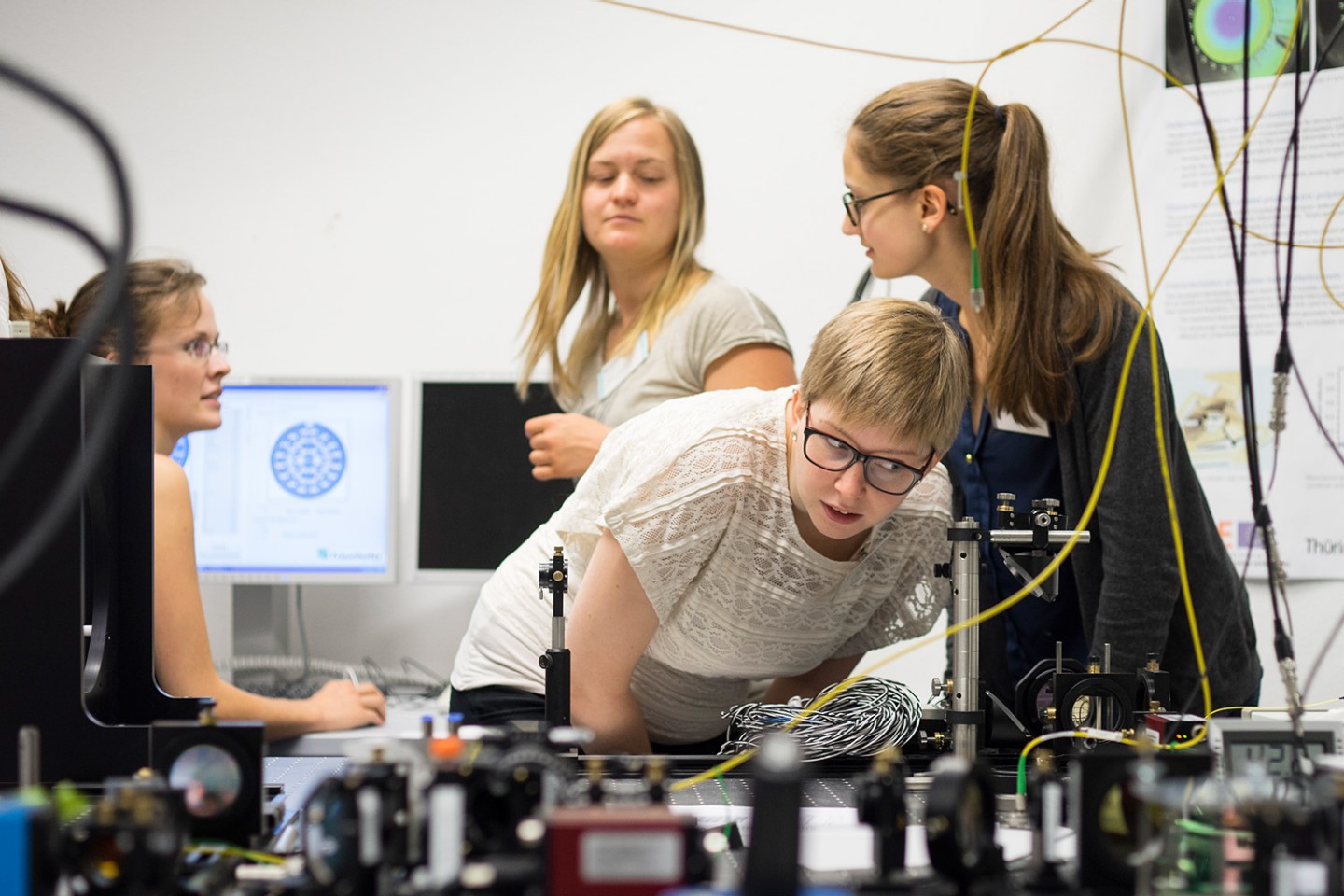 Vier Frauen in angeregter Unterhaltung über die Funktionalitäten eines Versuchaufbaus innerhalb des Fachgebietes adaptive Optik am Fraunhofer IOF während des Wissenschaftscampus 2016.