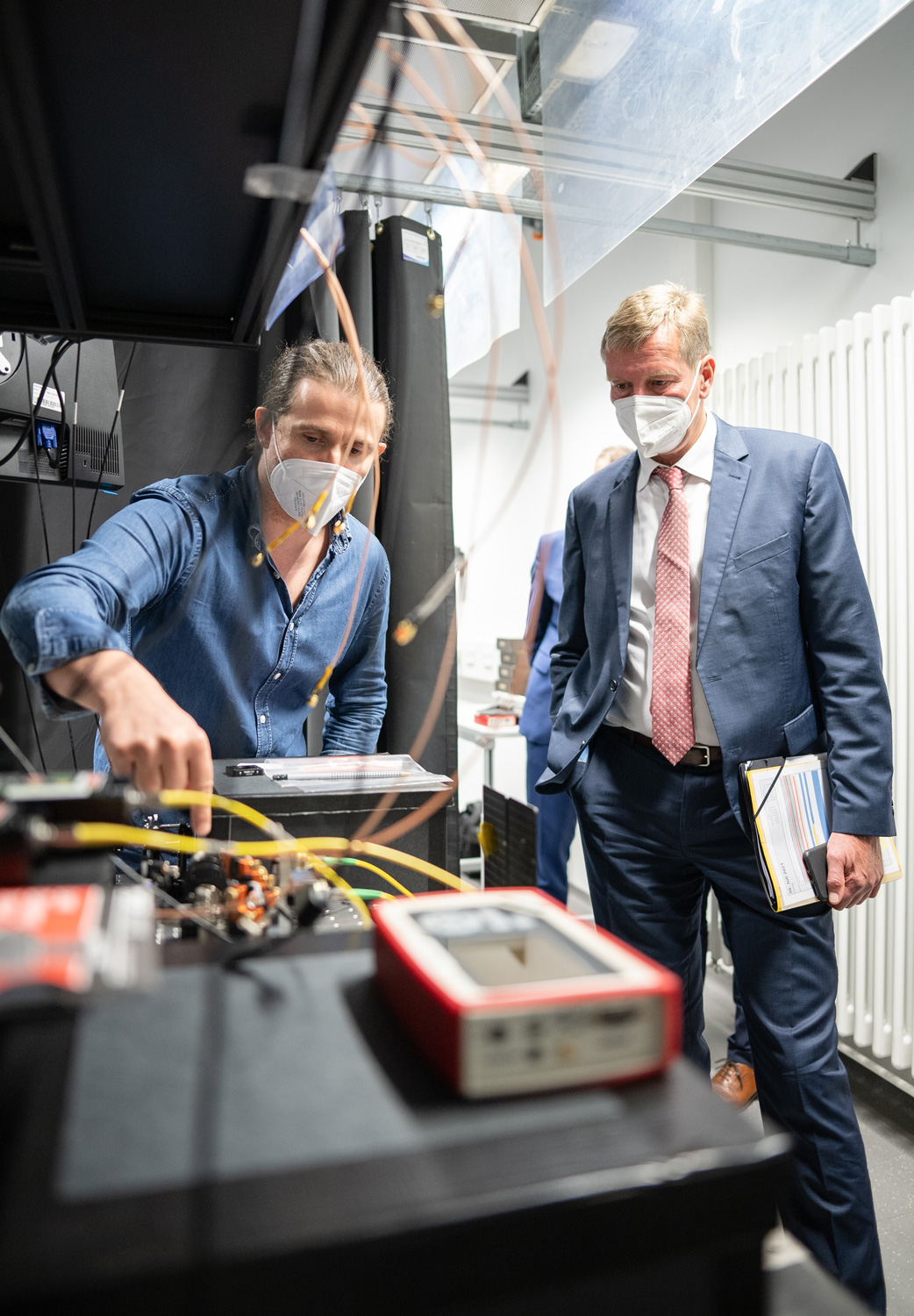 Quantenforscher Dr. Fabian Steinlechner erläutert Staatsekretär Carsten Feller einen optischen Laboraufbau.