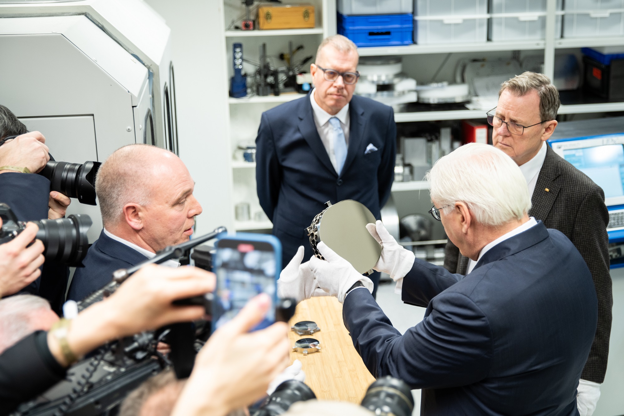 Der Bundespräsident besucht ein Labor zur Ultrapräzisionsfertigung und begutachtet eine Metalloptik.