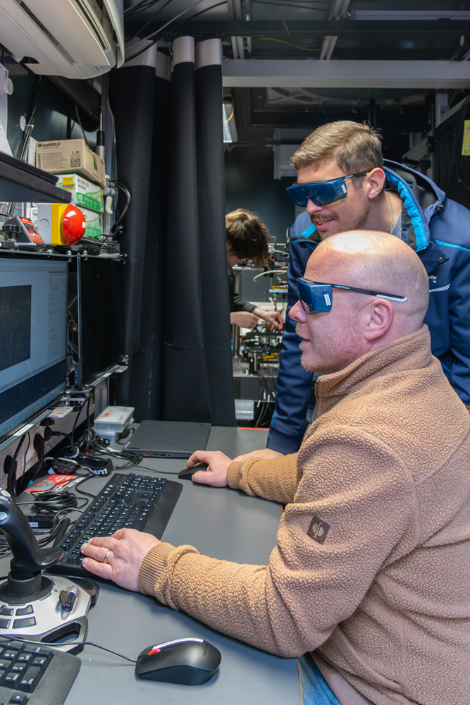 Blick ins Innere des Containers. Dort sitzen zwei Fraunhofer-Forscher an einem Schreibtisch und schauen auf einen PC-Bildschirm, um eingehende Signale auszuwerten.