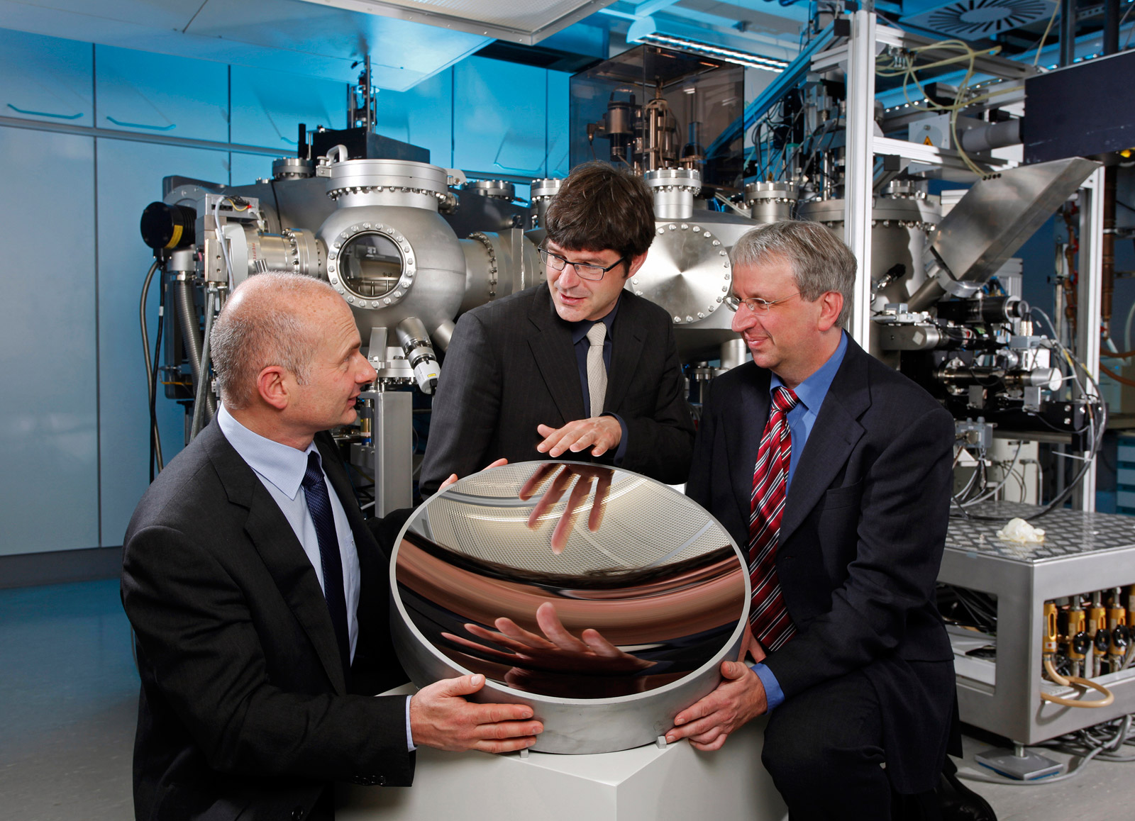 v. l. Dr. Tosten Feigl, Dr. Stefan Braun und Dr. Klaus Bergmann mit einem Kollektorspiegel.