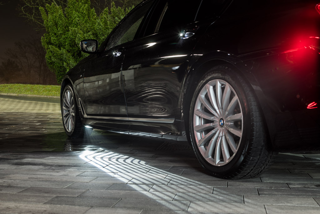 BMW 7er mit dem hell scheinenden Welcome Light Carpet neben der Fahrertür.