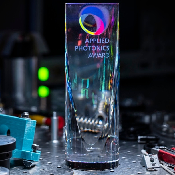 A glass  trophy stands on a work surface in the laboratory, surrounded by tools.