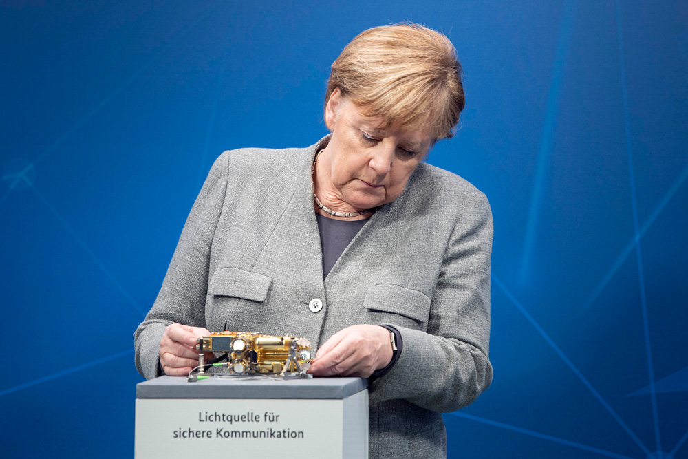German Chancellor Angela Merkel is examining a photon source at the 2020 Digital Summit.