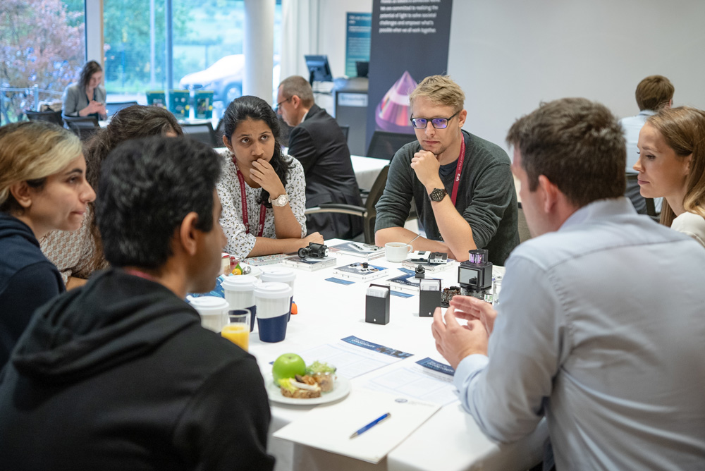 Students and doctoral candidates listen to a company presentation during breakfast.