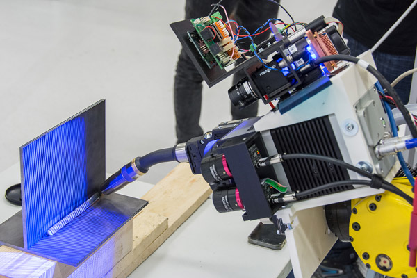 Robot with sensory measuring systems automatically welds a seam between metal plates.