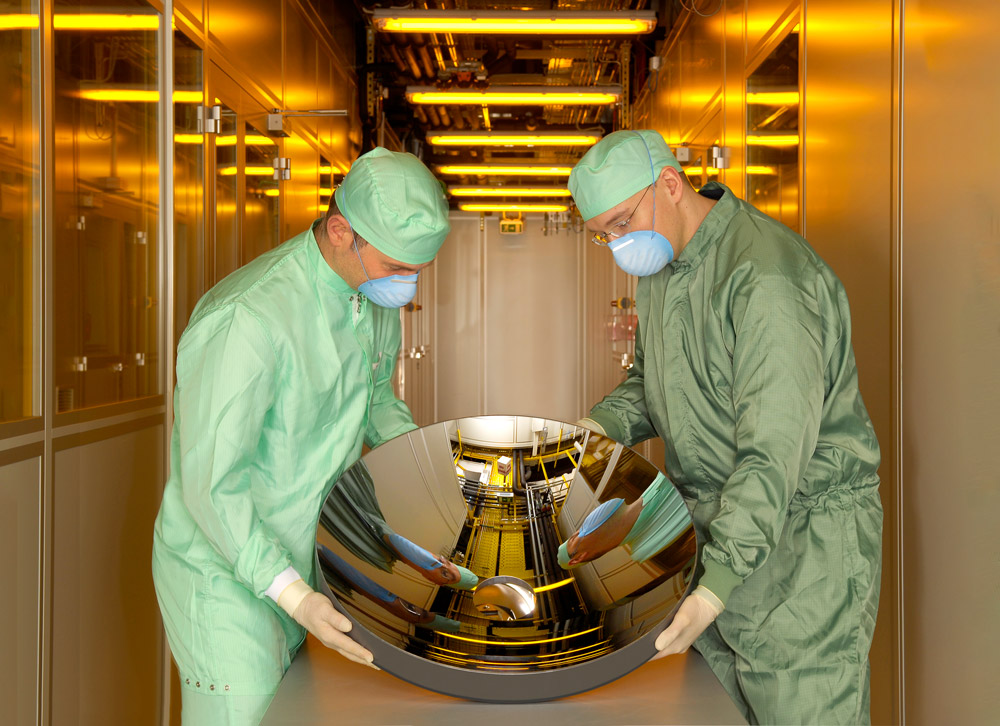 Two researchers together carry a collector mirror in their hands.