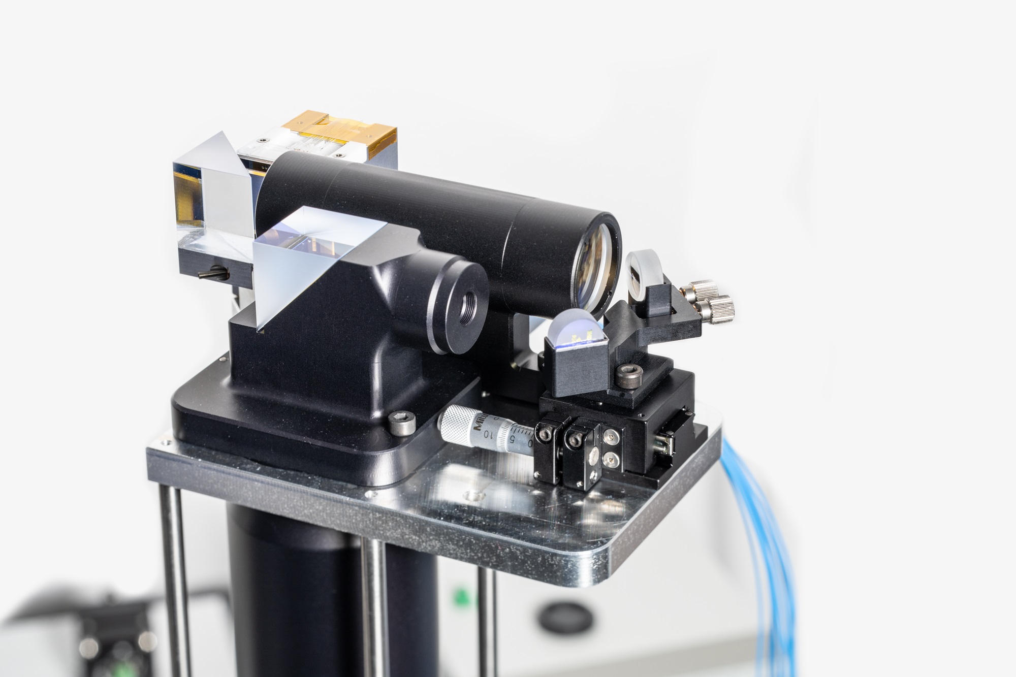 Two black tubes of different sizes with optical lenses are placed on a small metal table. Two beams of light point to these lenses.