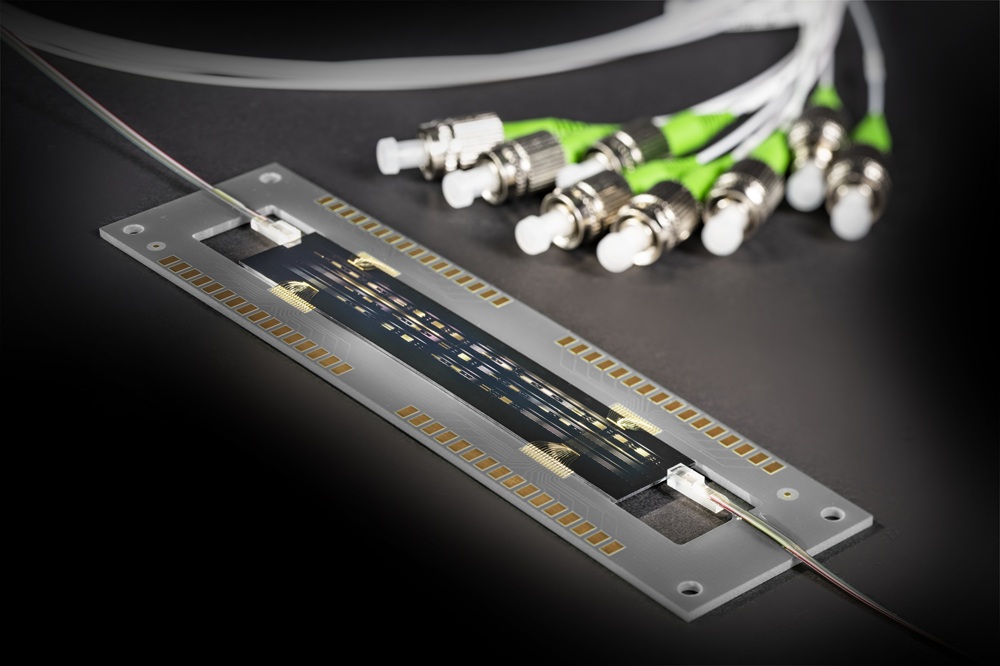 A metal plate. Gold dots are embedded along the long sides on the outside. A dark green plate with further golden dots is embedded in the middle. Two electrodes are attached to the short sides of the Greens plate.