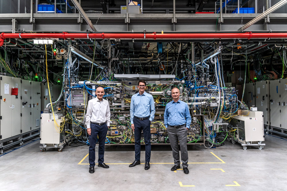 The development team in front of an industrial laser the size of a van.