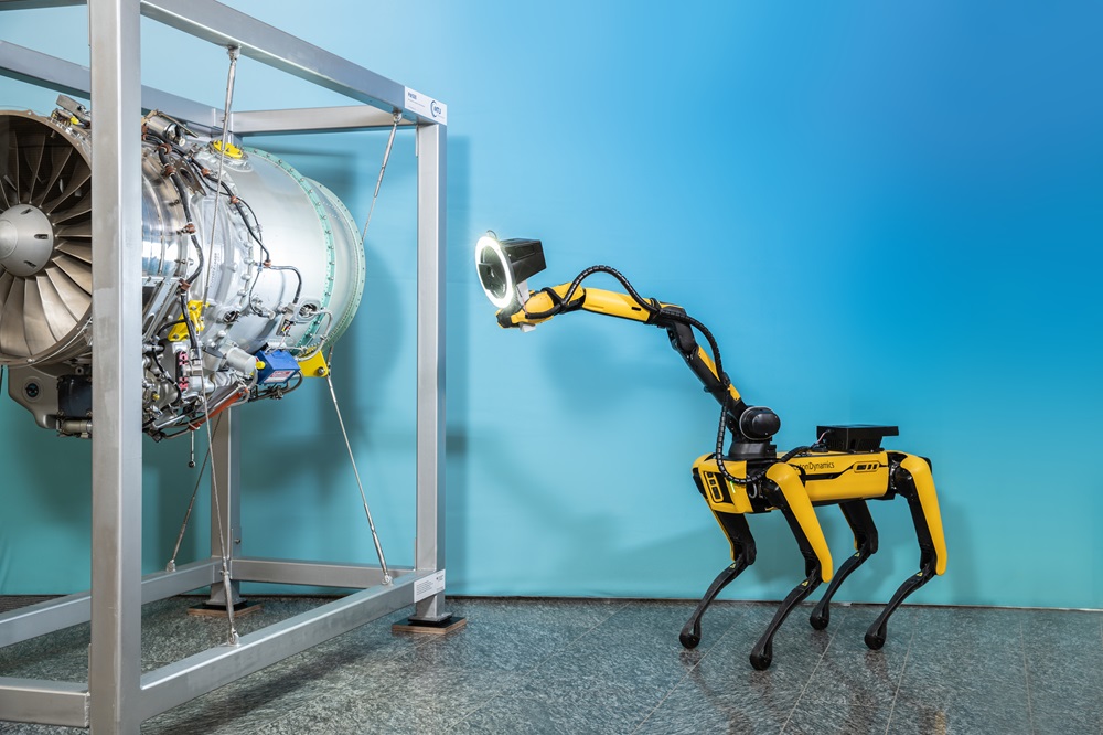 A yellow robot dog stands in front of a turbine and measures it using a 3D sensor.