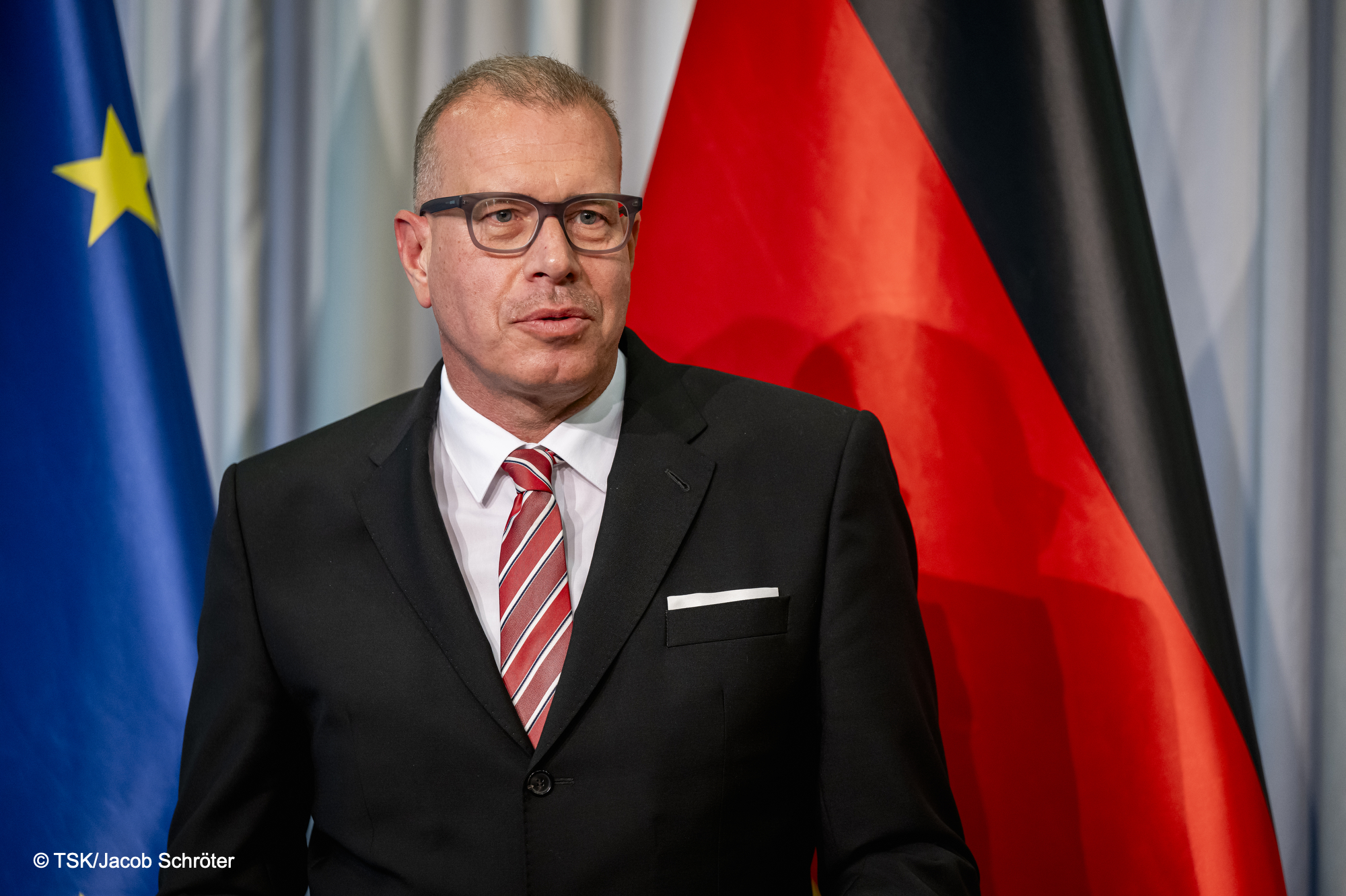 Photo of Andreas Tünnermann in front of the German and EU flags.
