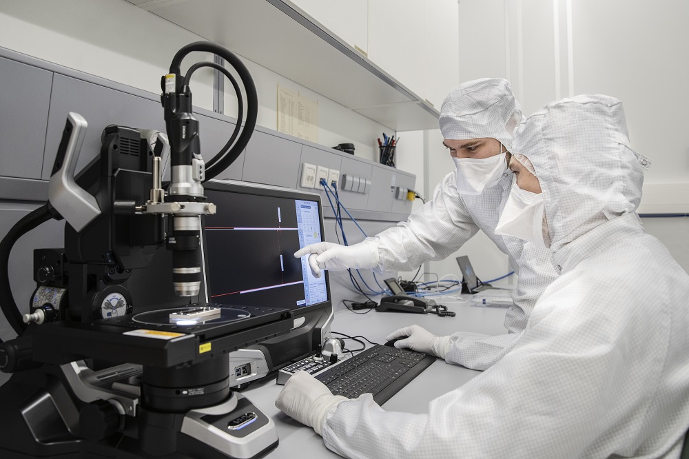 Researchers at Fraunhofer IOF look at the double slit under a microscope.