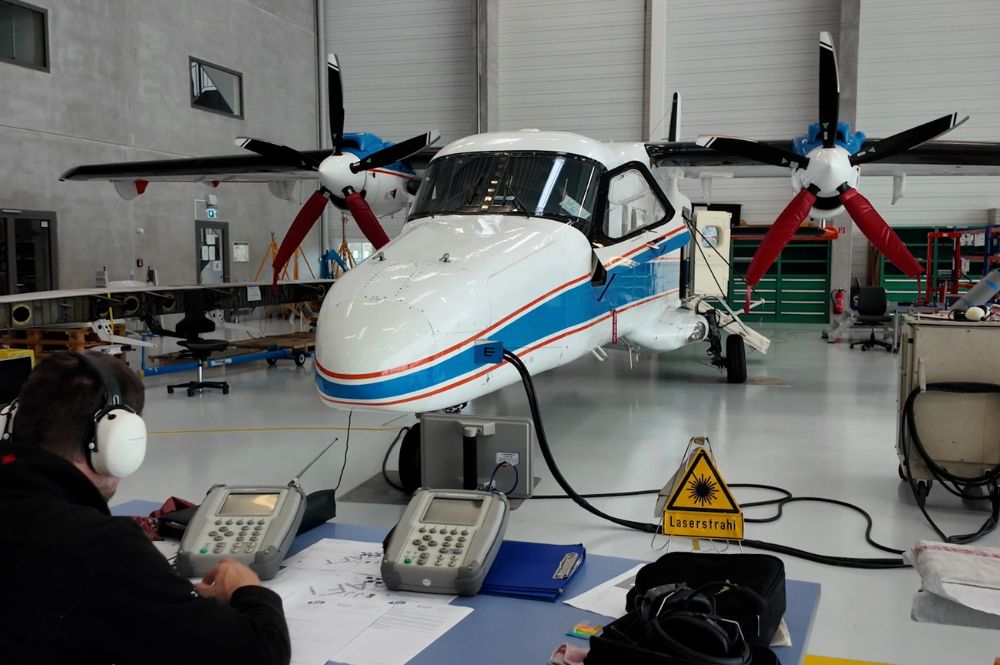 An airplane, and in front of it, a man is sitting at a desk.