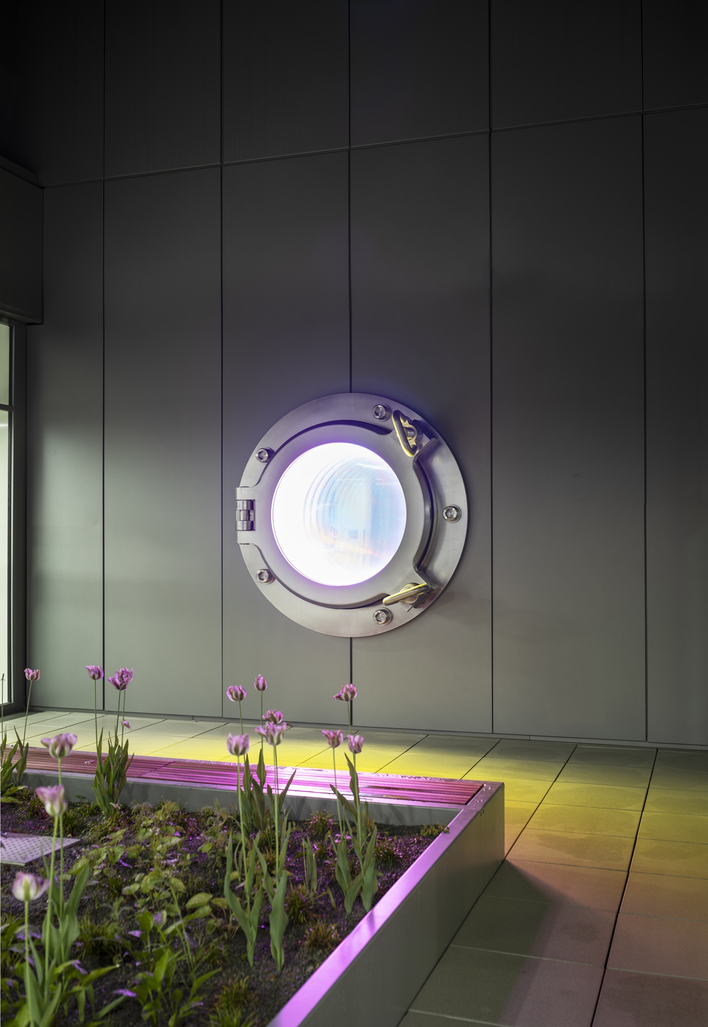 The oversized &#39;porthole&#39; is fitted into the façade and creates an illusionistic view into the wall through a double reflection and simultaneous transparency.